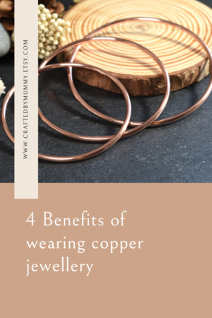 3 different sized shiny, round copper bangles displayed on a black slate with rustic props.  4 benefits of wearing copper jewellery