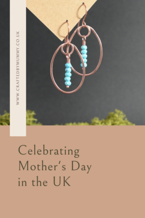 Copper and turquoise gemstone earrings display hanging from a piece of kraft card as an example of a gift idea for a mother on Mother's Day
