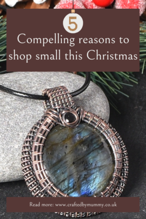 Discover the magic of local christmas fairs. 5 compelling reasons to shop small this christmas. A copper wire wrapped labradorite pendant with black cord displayed against a natural grey stone with a festive background of red berries and greenery